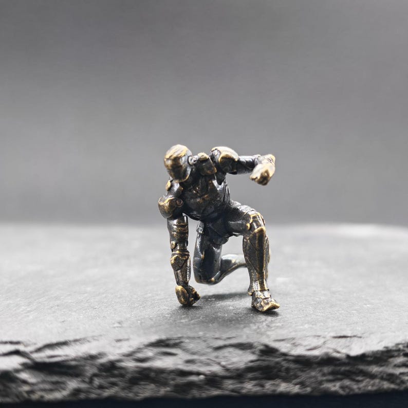 Brass Kneeling Armoured Hero Figurine — Red & Gold Exosuit Desk Collectible